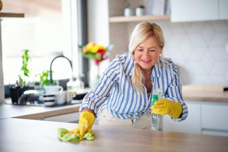 Portrait of senior woman cleaning kitchen counter indoors at home