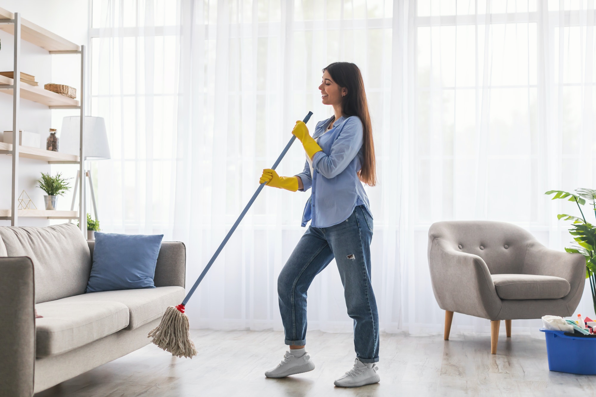 Woman cleaning floor singing and holding mop